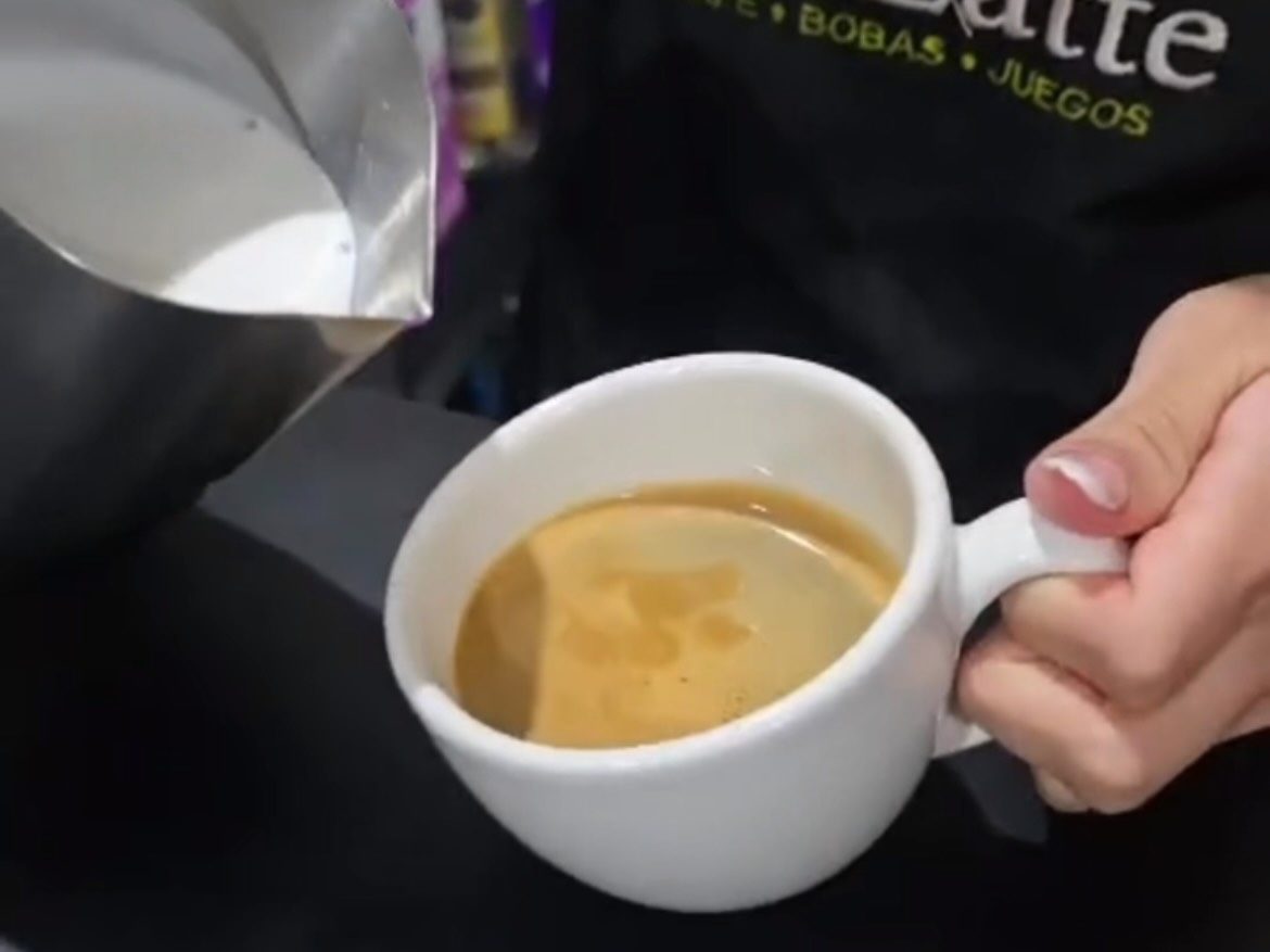 Barista de Té-Latte sirviendo leche en una taza de café